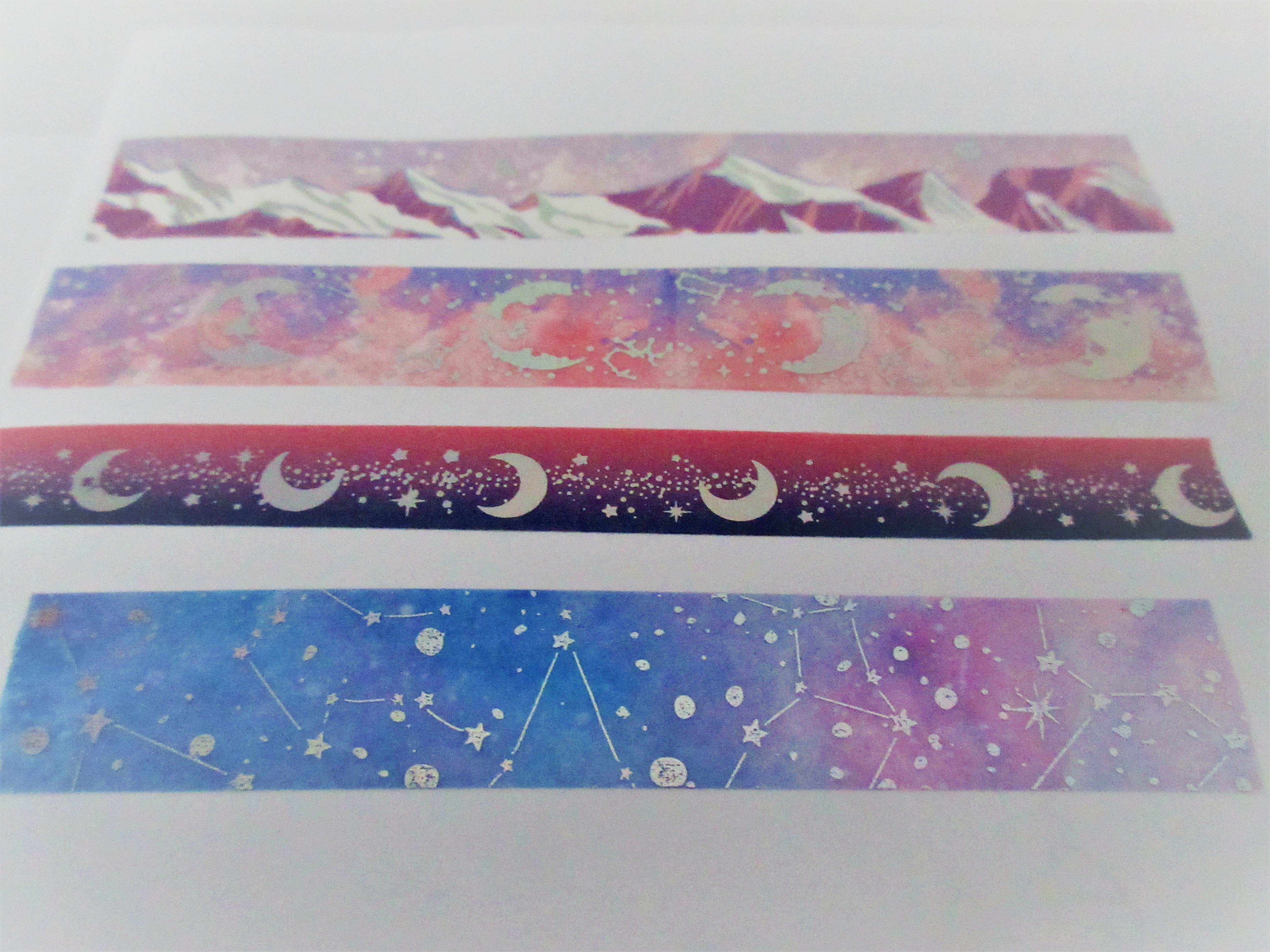 A variety of washi tape samples, including a crescent moon washi tape, with moons on a gradient background, a mountain washi tape sample and a constellations sample